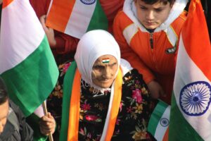 an elderly woman sitting with a group of people while holding a flag