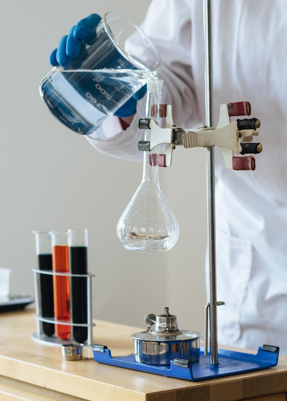 crop chemist pouring clear liquid into fragile glassware in science center