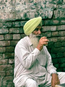elderly man enjoying beverage against brick wall