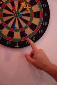 a close up shot of a person pointing to a dart board